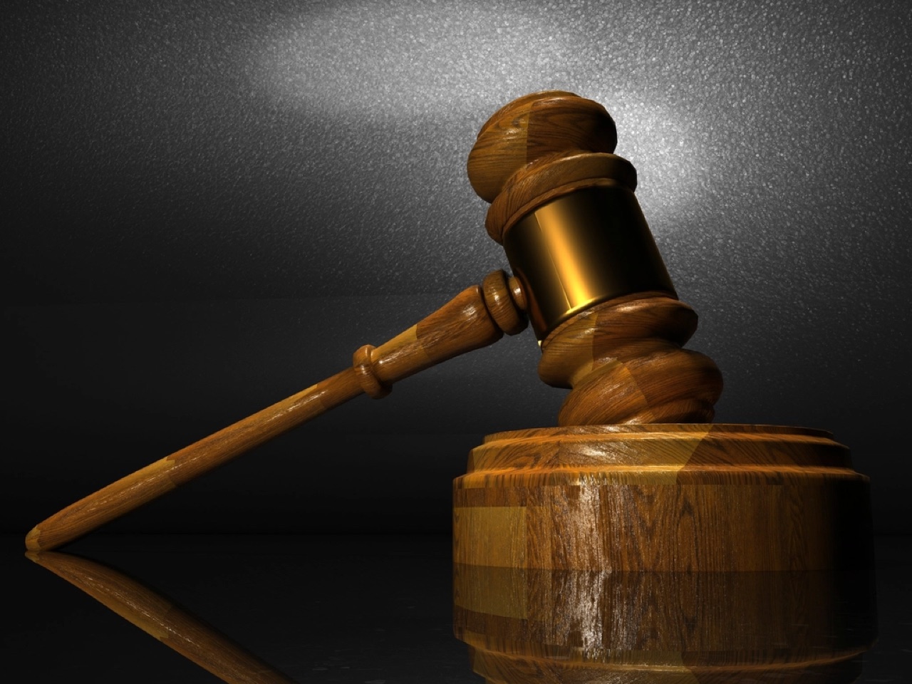 A wooden judge's gavel resting on a wooden surface.