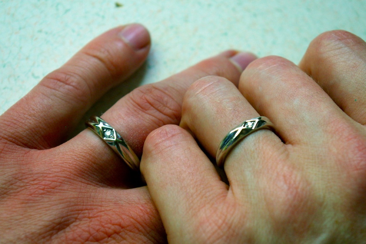 A close-up of a hand wearing a wedding ring.